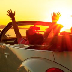 Happy family  in a cabriolet convertible car at the sunset in summer